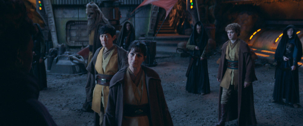 Lucasfilm announced that The Acolyte will arrive Tuesday, June 4, with a two-episode premiere on Disney+, and revealed the official key art for the series, featuring a hooded figure on a rocky landscape, as the sun sets in the distance. You can see it below, along with a poster released yesterday — which depicts a lightsaber on the ground, blood smeared ominously above.
