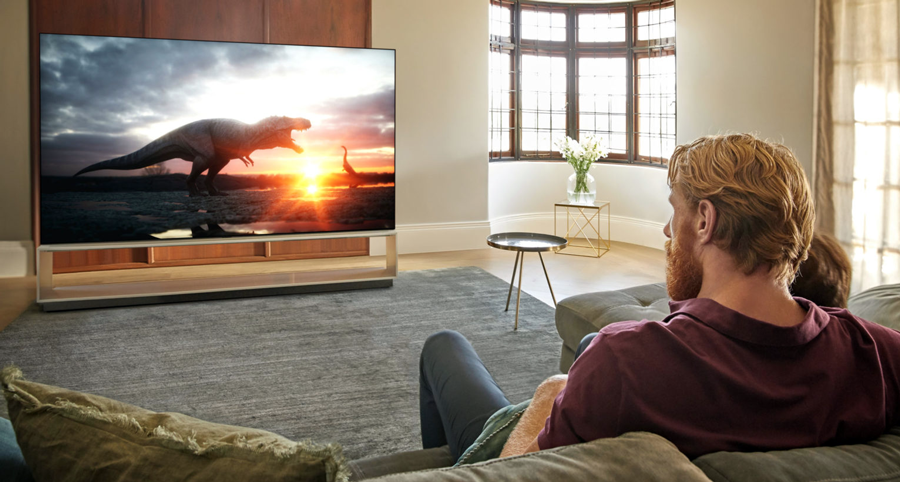 A lifestyle photo of a man sitting in front of a tv in a minimal living room