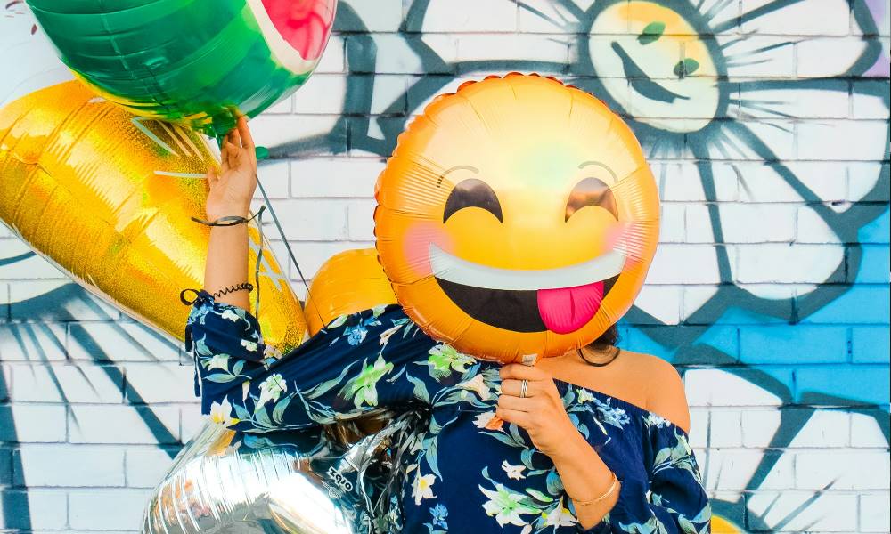 A person holding emoji baloons