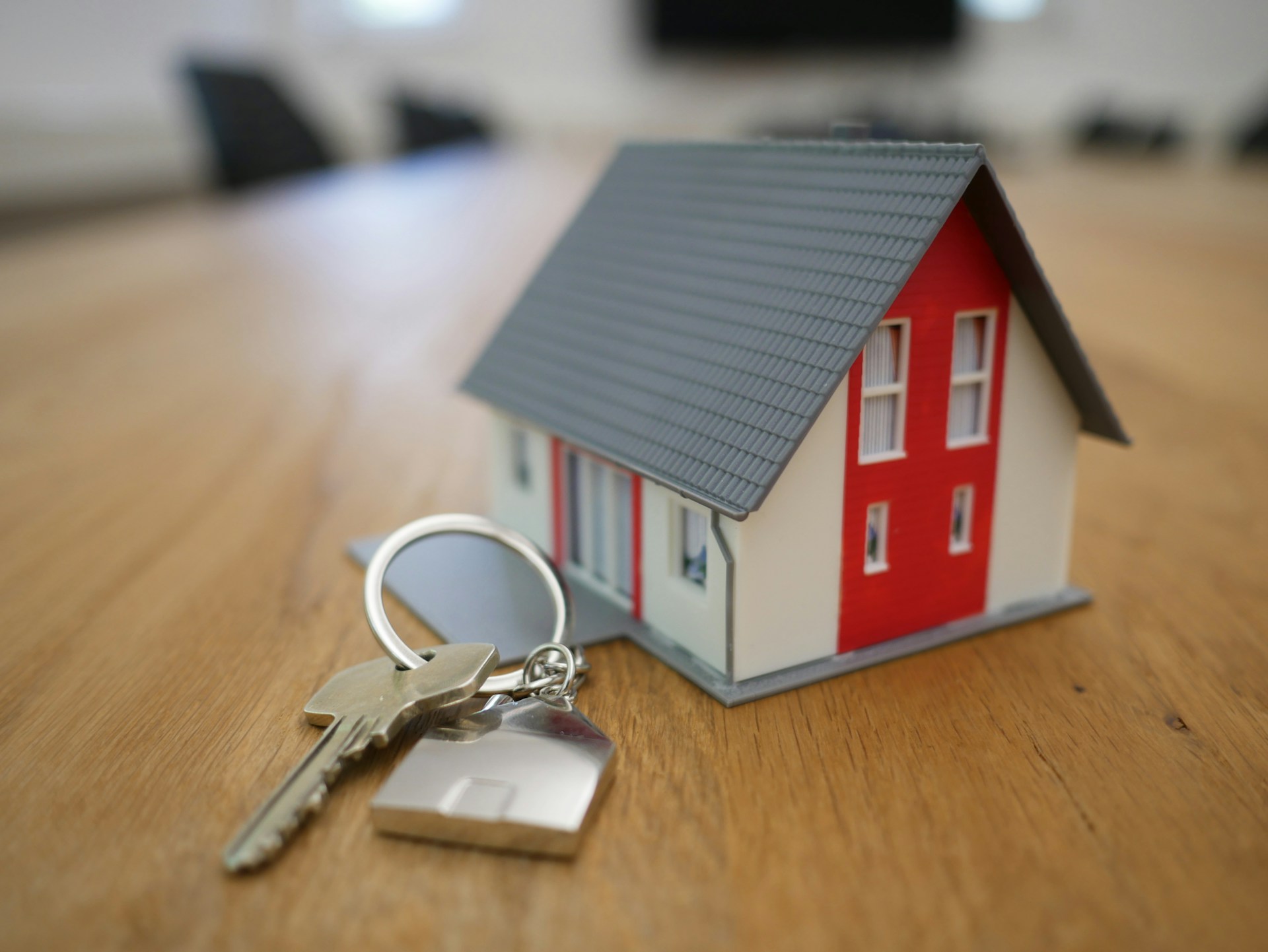 A miniature home and a home key on a wooden table