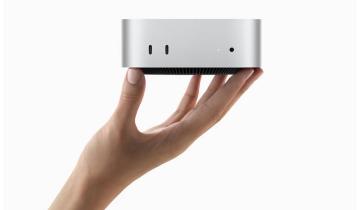 A hand holding a Mac Mini 