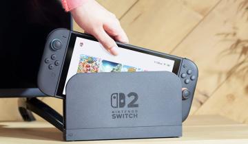 A hand lifting a Nintendo Switch 2 off its dock