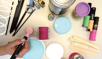 a DIY table with lots of supplies and a hand holding a pink marker